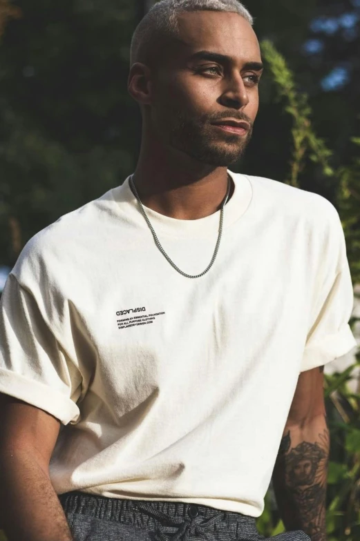 a man standing in front of a bush wearing a white t - shirt, inspired by Raphaël Collin, unsplash, neck chains, offwhite, detailed product shot, sythwave