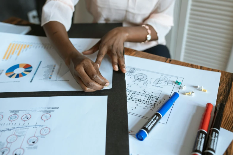 a woman sitting at a table working on a project, a detailed drawing, by Carey Morris, pexels contest winner, charts, holding close, whiteboards, background image