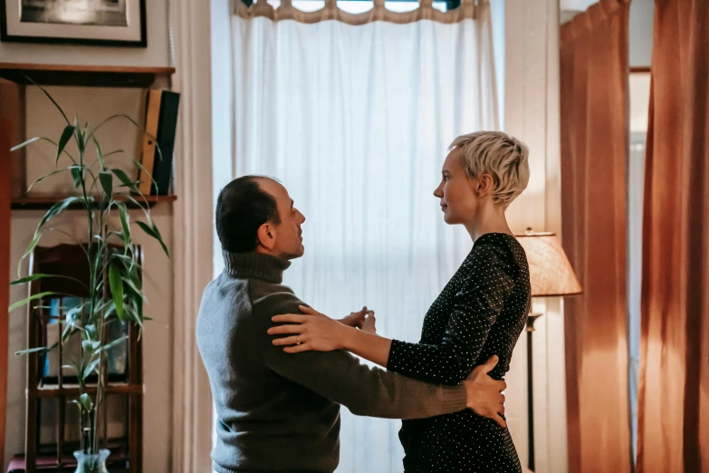 a man standing next to a woman in a living room, by Carey Morris, pexels contest winner, holding each other, profile image, background image, emily rajtkowski