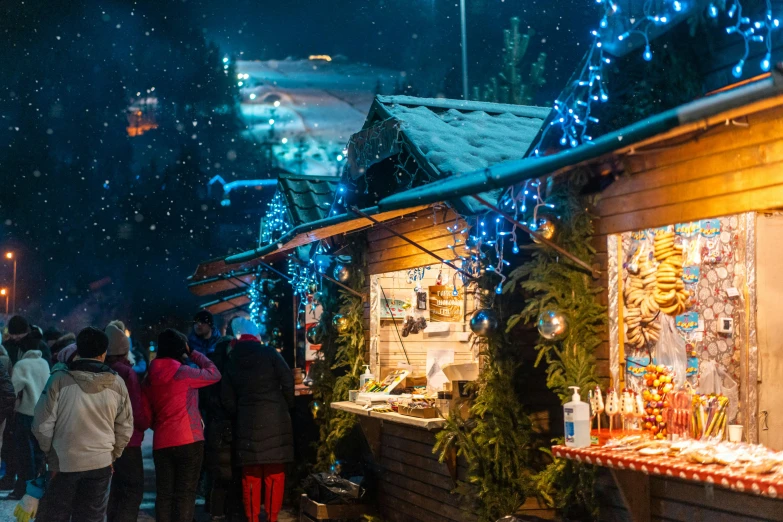 a group of people standing around a christmas market, by Julia Pishtar, pexels contest winner, stood outside a wooden cabin, blue and red lights, whistler, gourmet and crafts