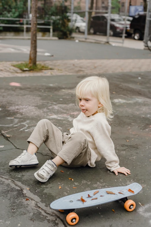 a small child sitting on the ground next to a skateboard, pexels contest winner, eva elfie, wearing a track suit, white, distressed