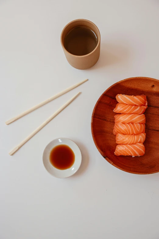 a plate of sushi and chopsticks next to a cup of coffee, inspired by Tōshi Yoshida, purism, salmon, wood cups, trending on dezeen, clean glow