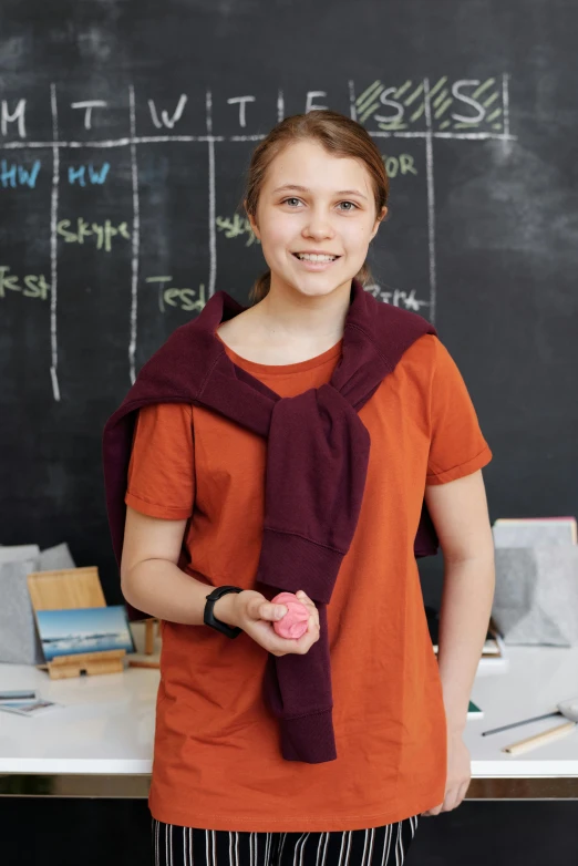 a young woman standing in front of a blackboard, inspired by Caspar van Wittel, shutterstock contest winner, process art, holding a ball, cloth wraps, young teen, scientific photo