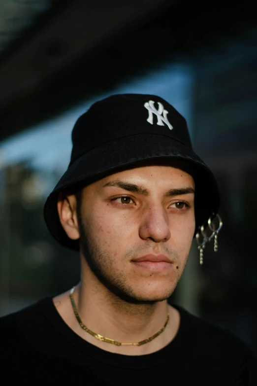 a close up of a person wearing a hat, an album cover, inspired by Ion Andreescu, unsplash, hyperrealism, he is wearing a black t-shirt, bucket hat, serious expression, humans of new york style