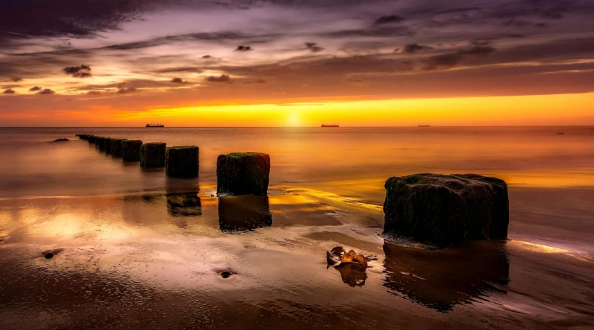 a group of wooden posts sitting on top of a sandy beach, by Andries Stock, pexels contest winner, autumn sunset, floating stones, youtube thumbnail, coloured photo