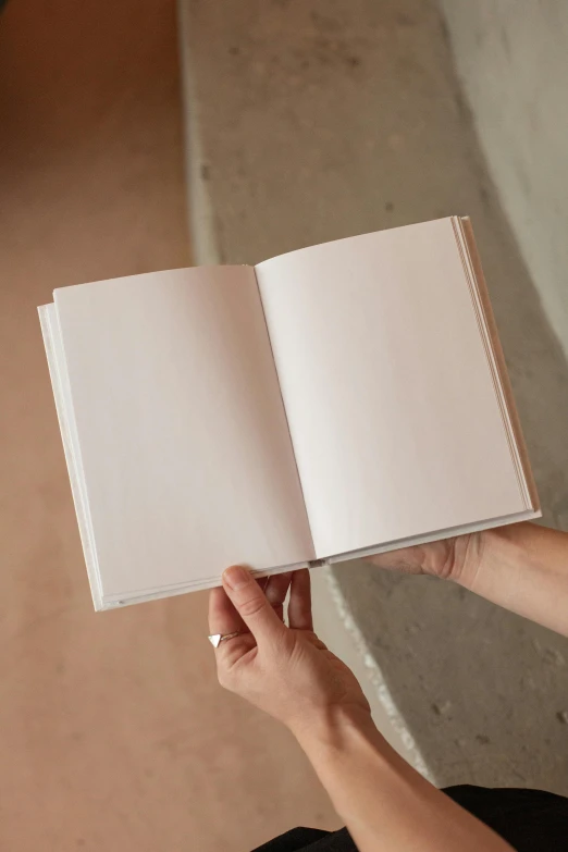 a person holding an open book in their hands, by Nina Hamnett, happening, soft white rubber, notebook, large, handcrafted