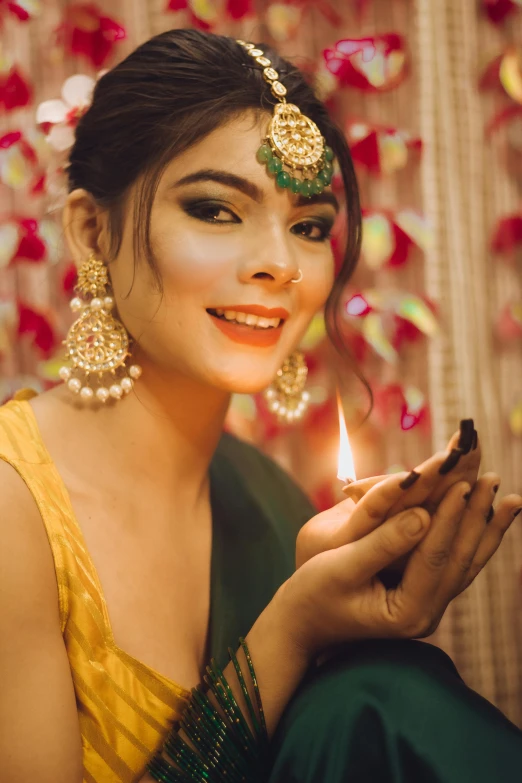 a woman holding a lit candle in her hand, a picture, by Riza Abbasi, pexels, wearing festive clothing, yellow makeup, beautiful young himalayan woman, a handsome