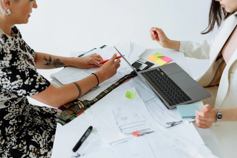 two women sitting at a table with papers and a laptop, pexels contest winner, arbeitsrat für kunst, industrial design blueprint, office clothes, with notes, white background and fill