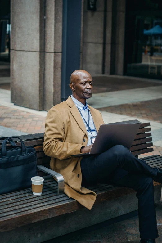 a man sitting on a bench with a laptop, tech robes, george pemba, multiple stories, middle aged man