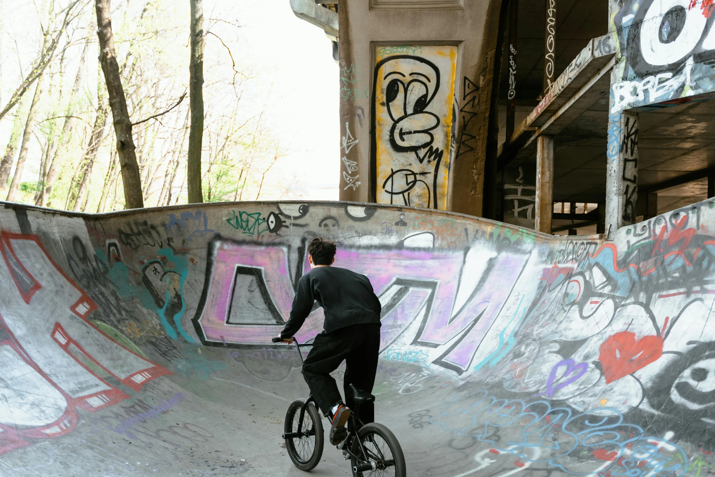 a man riding a bike up the side of a ramp, a picture, graffiti, bowl, berlin park, cavernous, brown