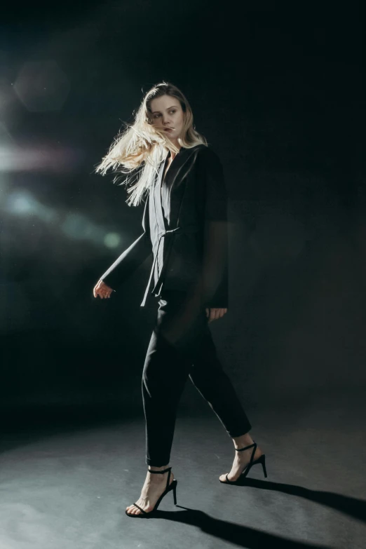 a woman in high heels walking in the dark, inspired by Peter Lindbergh, unsplash, wearing a track suit, elle fanning), dark. studio lighting, wearing causal black suits