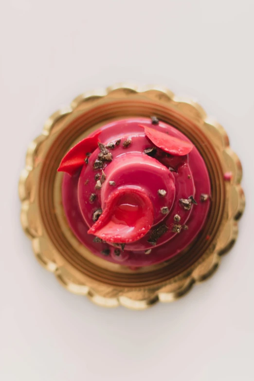 a cupcake sitting on top of a gold plate, red beryl, profile image, view from above, david kassan