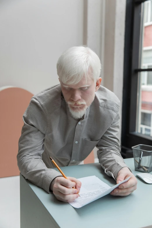 a man sitting at a table writing on a piece of paper, inspired by Sigurd Swane, trending on reddit, intense albino, ignant, going gray, professional modeling