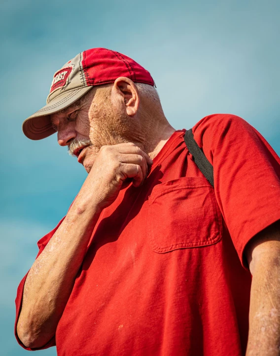 a man in a red shirt talking on a cell phone, by Arnie Swekel, pexels contest winner, wearing farm clothes, head bowed slightly, profile image, grandfatherly