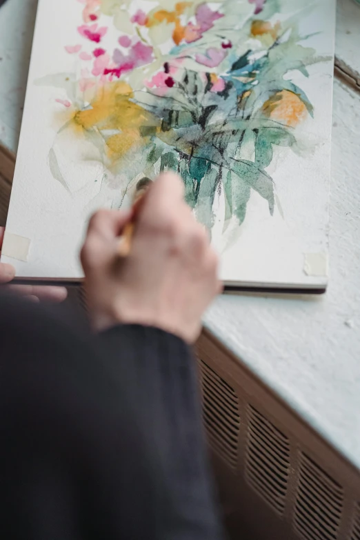 a close up of a person working on a painting, a watercolor painting, inspired by Richard Schmid, pexels contest winner, botanicals, on a yellow canva, on a white table, architectural painting
