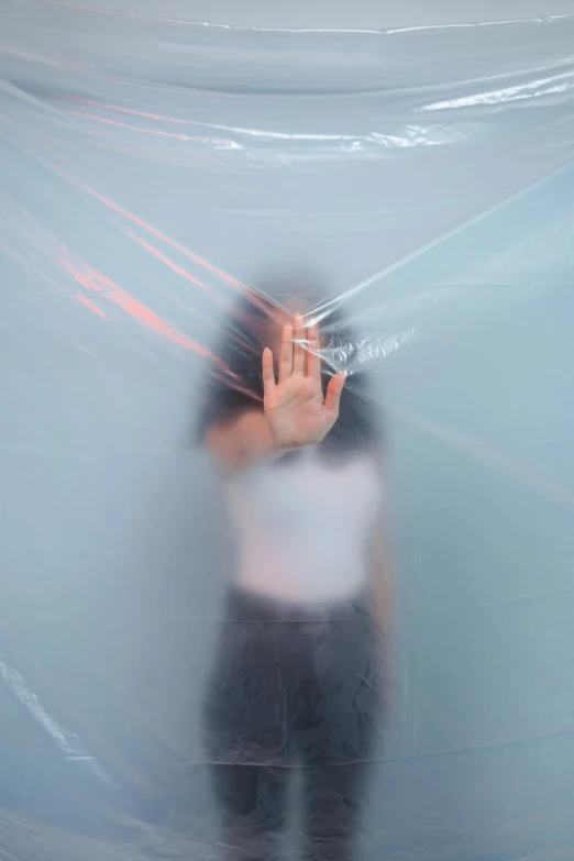 a blurry image of a person holding a cell phone, an album cover, inspired by Cornelia Parker, unsplash, interactive art, draped in transparent cloth, inflatable, containment pod, hand gesture