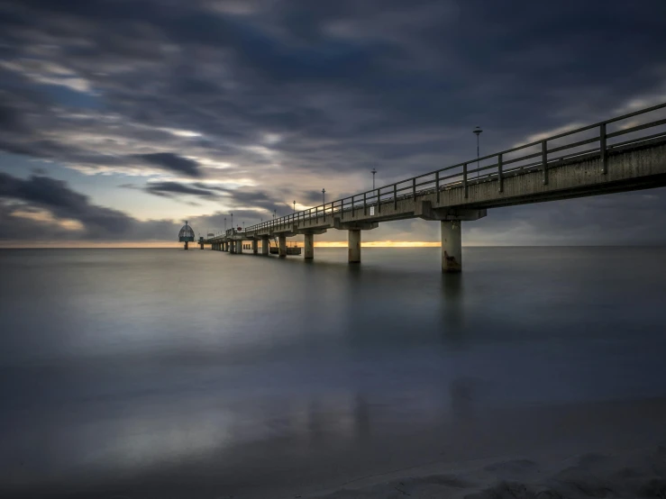 a bridge over a body of water under a cloudy sky, by Wolfgang Zelmer, long exposure photo, fan favorite, seaside, soft light - n 9