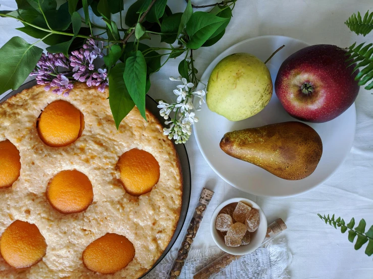 a cake sitting on top of a white plate next to a bowl of fruit, a still life, inspired by Gentile Bellini, trending on pexels, pears, with fruit trees, hippie pad, thumbnail