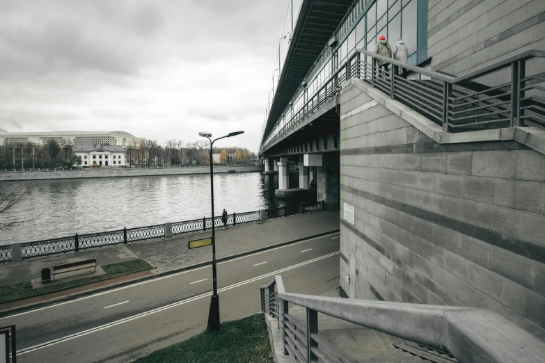 a man riding a skateboard down a sidewalk next to a river, by Serhii Vasylkivsky, brutalism, stadium, high resolution photo, grey, two stories