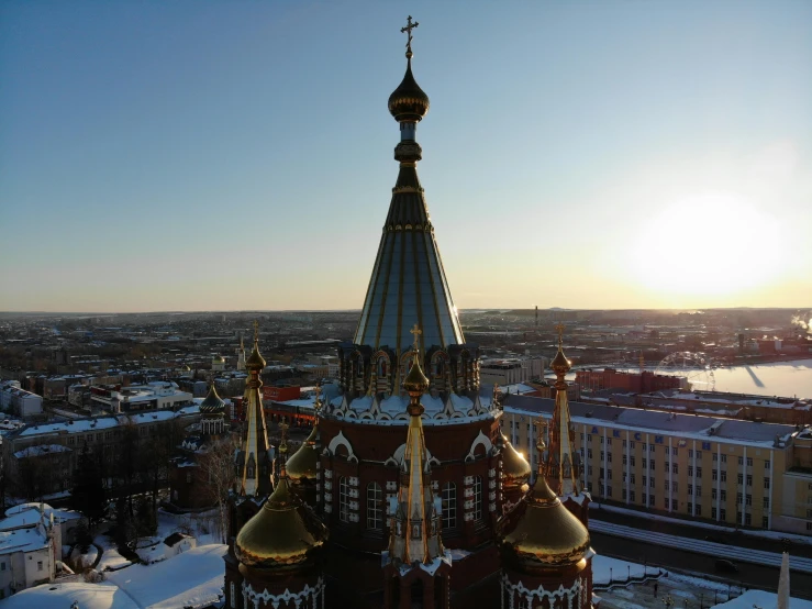 an aerial view of a church in the snow, inspired by Vasily Surikov, pexels contest winner, art nouveau, evening sunlight, brown, spire, faberge