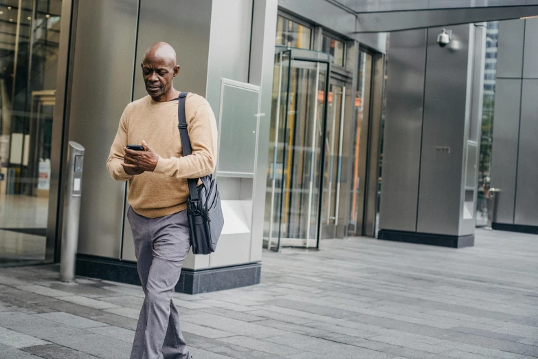 a man walking down the street looking at his cell phone, bald man, diverse, thumbnail, professional image