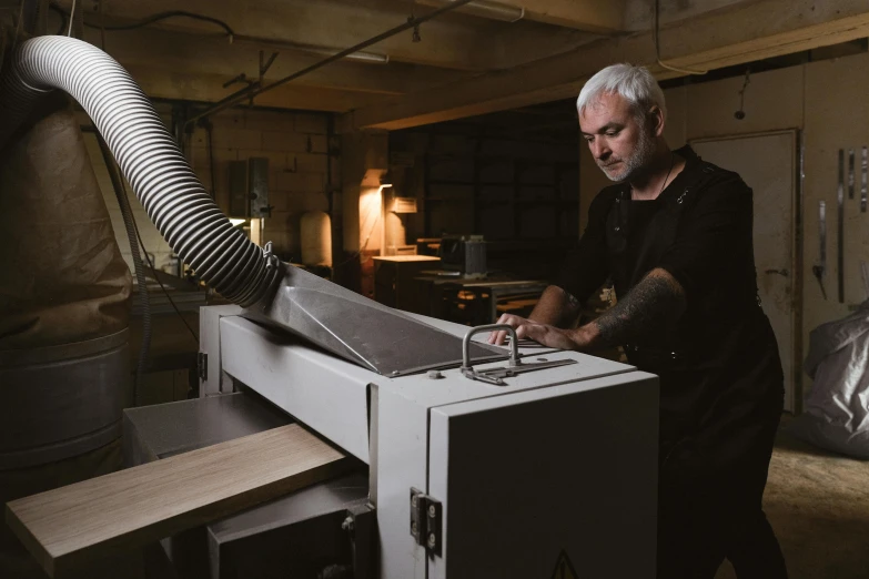 a man working on a machine in a workshop, a portrait, pexels contest winner, private press, john pawson, cedar, crisp smooth clean lines, white