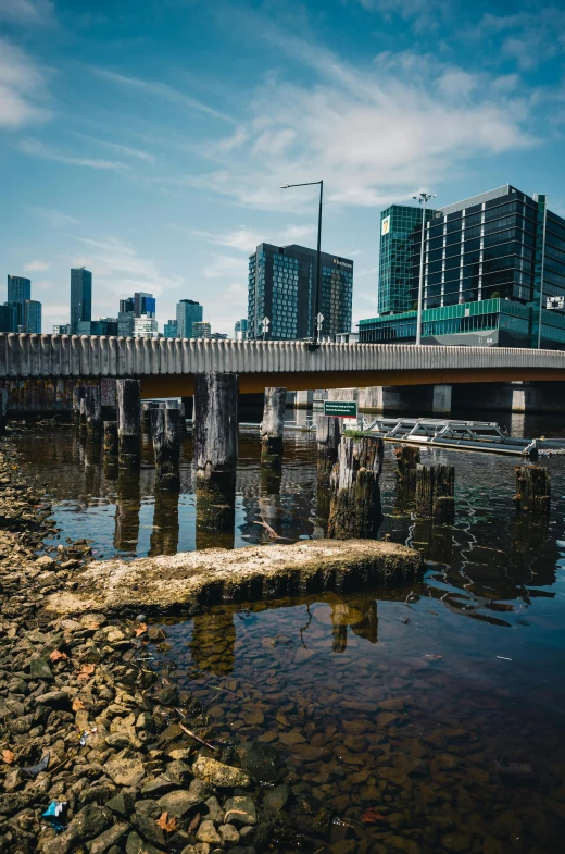 a bridge over a body of water with buildings in the background, by Jason Felix, unsplash, melbourne, fallen columns, a wooden, inlets