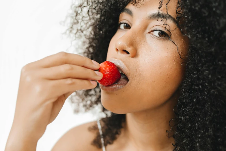 a close up of a person eating a strawberry, she has olive brown skin, skincare, thumbnail, slightly pixelated