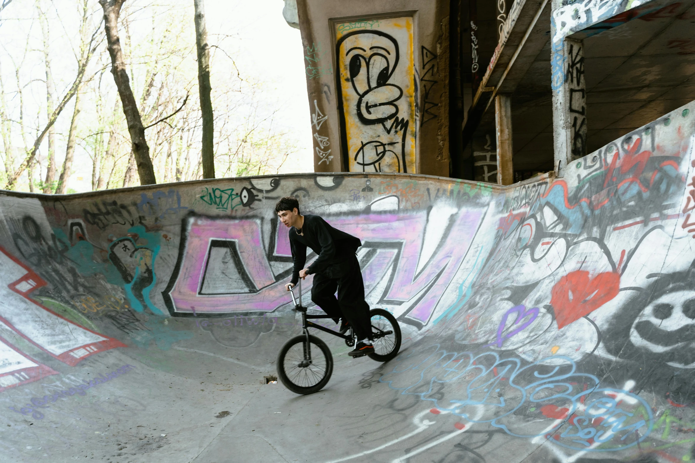 a man riding a bike up the side of a ramp, a picture, graffiti, snacks, circle pit, black