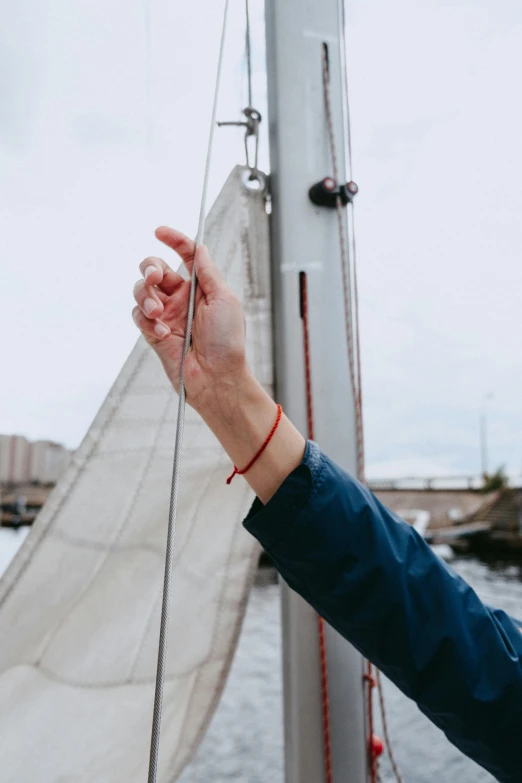 a woman standing on top of a boat next to a body of water, by Jan Tengnagel, unsplash, close-up of thin soft hand, sails, holding a stuff, pointing index finger