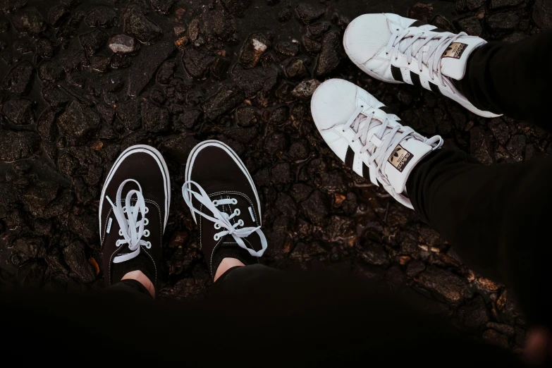 a couple of people that are standing in the dirt, pexels contest winner, sneakers, white on black, sisters, different styles