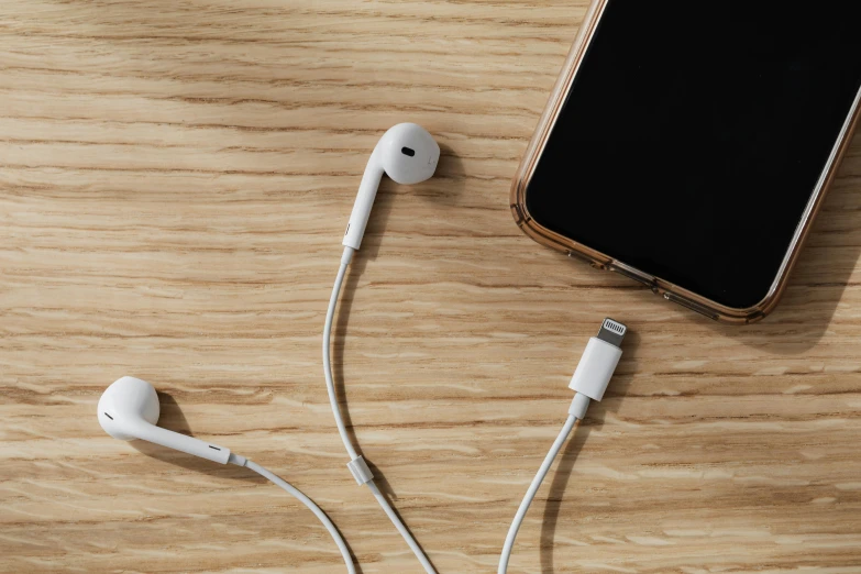 a cell phone sitting on top of a wooden table, earbuds jewelry, detailed product image, cable, detail shot