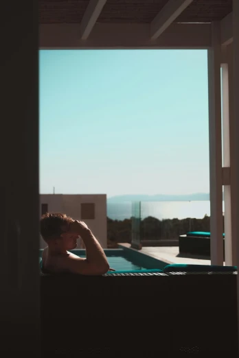 a person sitting in a chair looking out a window, greek pool, cinematic shot ar 9:16 -n 6 -g, low quality photo, ibiza