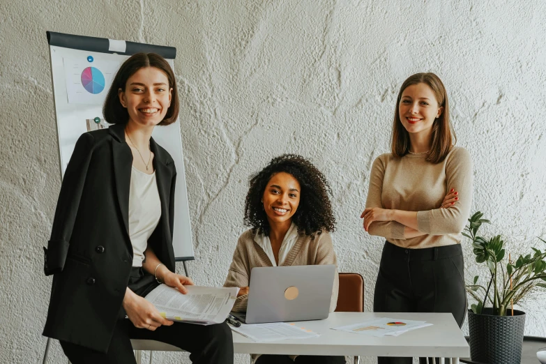 three women sitting at a table with a laptop, pexels contest winner, standing on a desk, professional branding, profile image, group photo