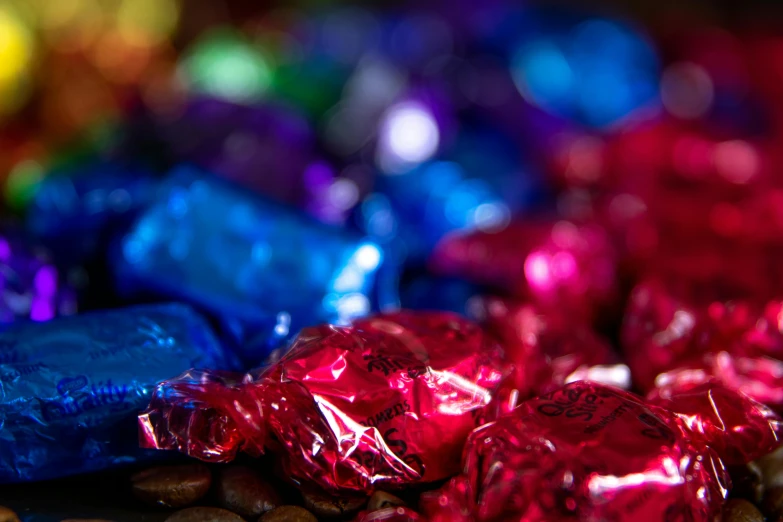 a pile of candy sitting on top of a pile of coffee beans, by Julia Pishtar, brand colours are red and blue, shiny colors, thumbnail, shot on sony a 7