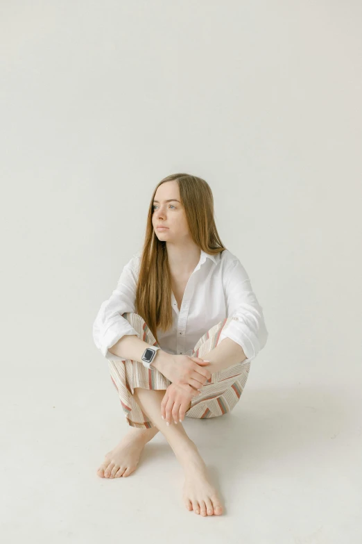 a woman sitting on the ground with her legs crossed, unsplash, renaissance, white backdrop, wearing a linen shirt, with long hair, thoughtful )