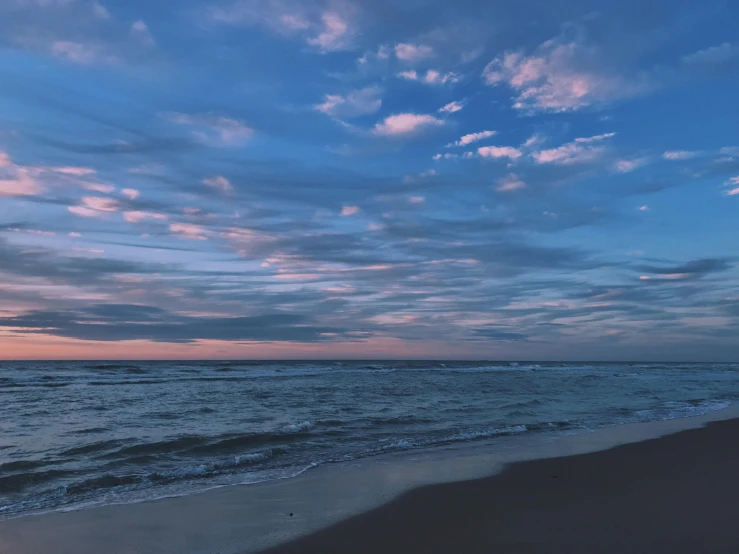 a large body of water sitting on top of a sandy beach, a picture, unsplash contest winner, romanticism, cotton candy clouds, at gentle dawn blue light, # nofilter, near the seashore