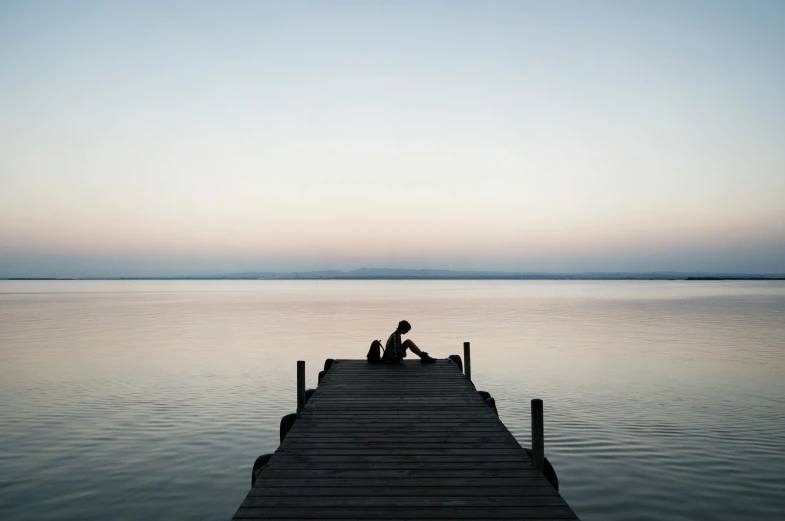 a person sitting on a dock in the middle of a body of water, minimalism, 2 people, early evening, comforting, ignant