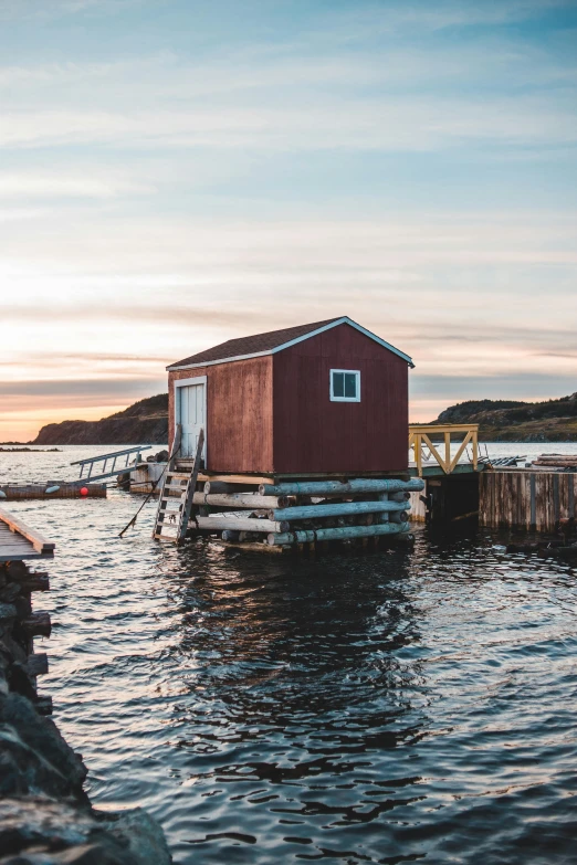 a red boathouse sitting on top of a body of water, by Jessie Algie, pexels contest winner, archipelago, built around ocean, 2 0 2 2 photo, small port village