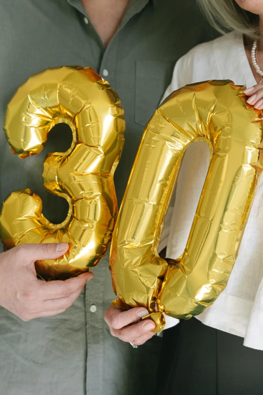 a woman standing next to a man holding a gold balloon, instagram, happening, 3 0 years woman, 3 colours, inflateble shapes, close up details