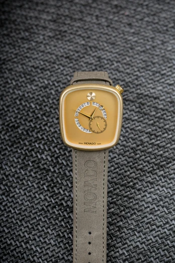 a close up of a watch on a cloth, inspired by Pedro Pedraja, accented in bright metallic gold, front view dramatic, square, twin motion