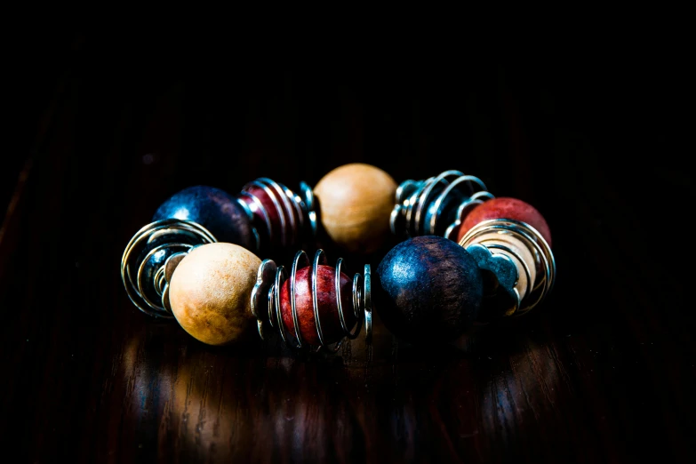 a close up of a bracelet on a table, by Thomas Häfner, unsplash, process art, brown red blue, ivory and ebony, spheres, copper spiral hair decorations