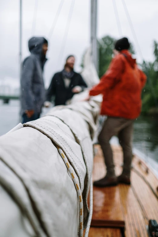 a group of people standing on top of a boat, by Jessie Algie, unsplash, renaissance, rainy outside, sailboat, organic detail, lined in cotton