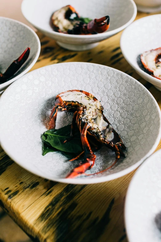 a close up of plates of food on a table, a portrait, unsplash, mingei, lobster, bowl, charred, patterned