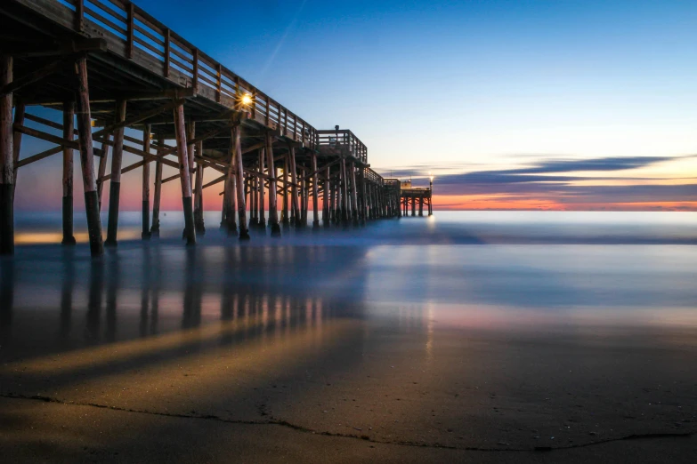 a pier sitting on top of a sandy beach, pexels contest winner, renaissance, sunrise colors, liquid light, multiple stories, lynn skordal