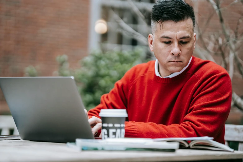 a man sitting at a table using a laptop computer, a portrait, pexels contest winner, red sweater and gray pants, schools, lachlan bailey, asian male