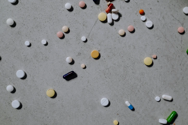 a table topped with lots of different colored pills, by Jan Rustem, unsplash, plasticien, on the concrete ground, animation, ignant, scattered