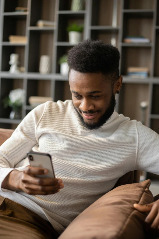 a man sitting on a couch using a cell phone, trending on pexels, renaissance, wearing a white sweater, man is with black skin, wholesome, reading