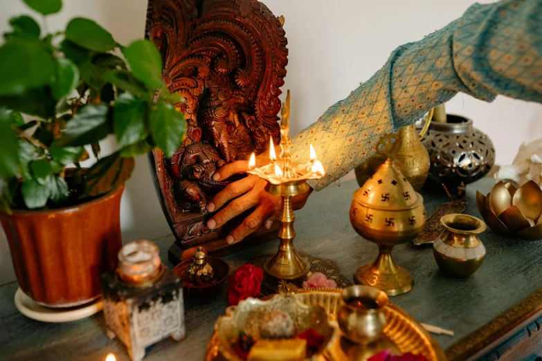 a person lighting a candle on a table, hurufiyya, hindu aesthetic, profile image, thumbnail, displayed on an altar