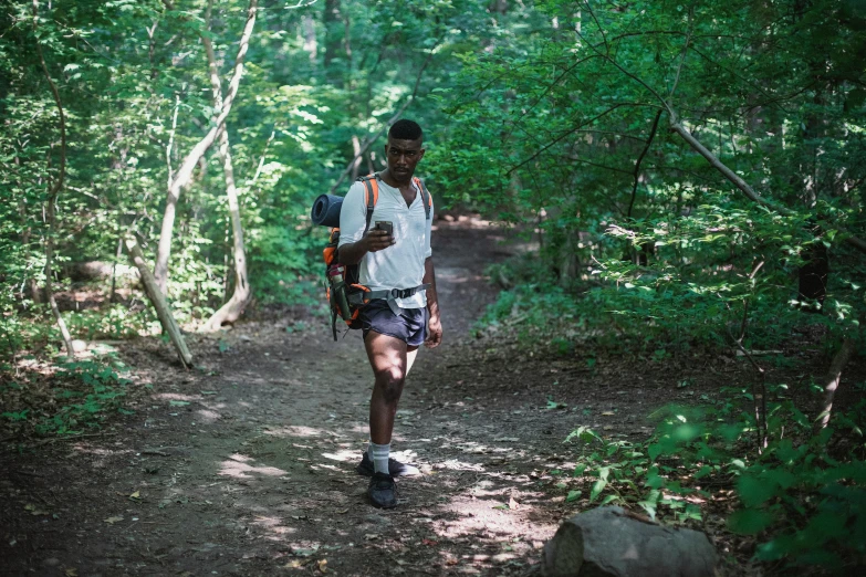 a man walking down a dirt path in the woods, dark skinned, white shorts and hiking boots, avatar image